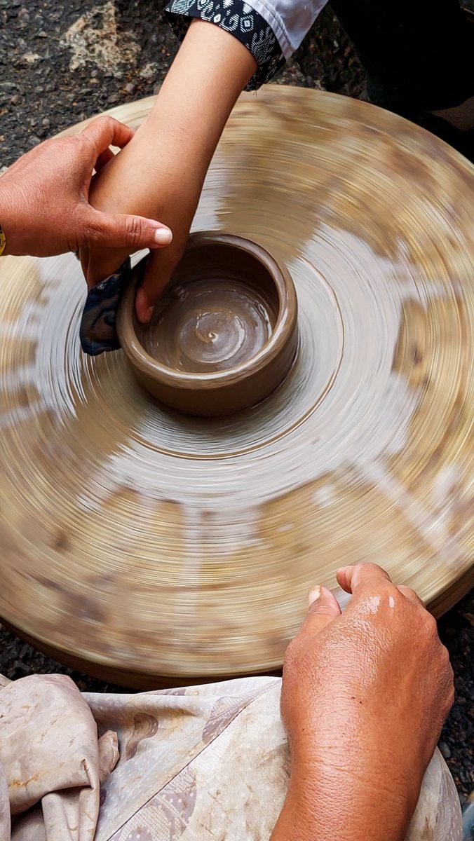 Hands shaping clay on a pottery wheel
